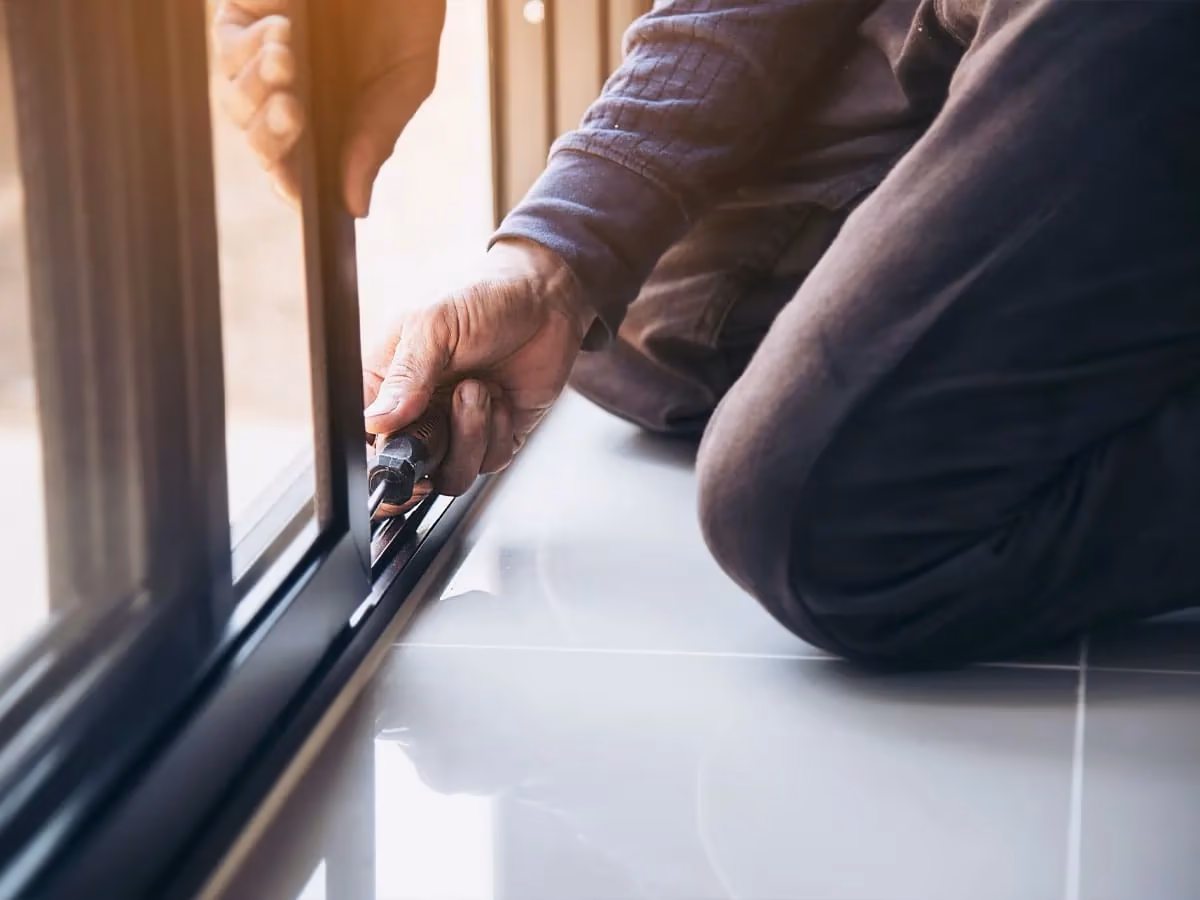 Técnico revisando y ajustando una puerta automática de vidrio.