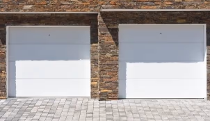 Puertas de garaje blancas en fachada de ladrillo.