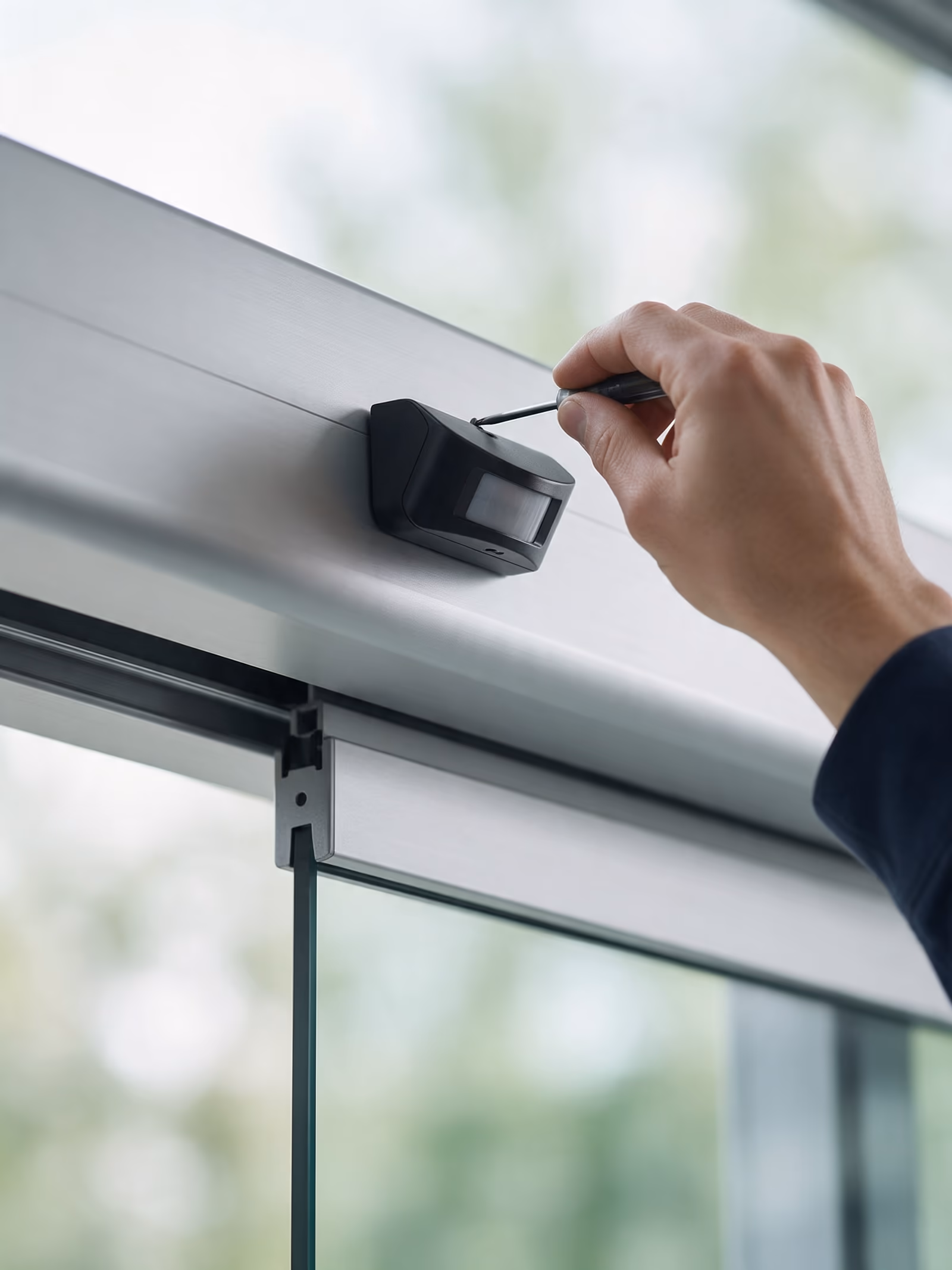 Técnico ajustando el sensor de detección de una puerta automática de cristal