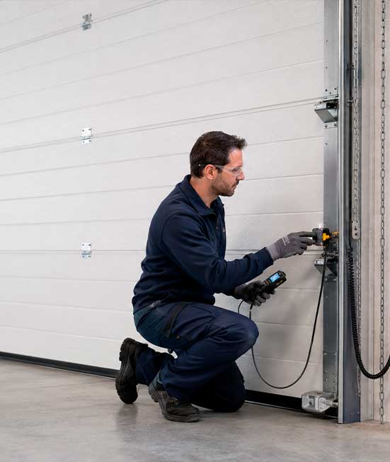 Técnico realizando el mantenimiento preventivo de una puerta industrial automática